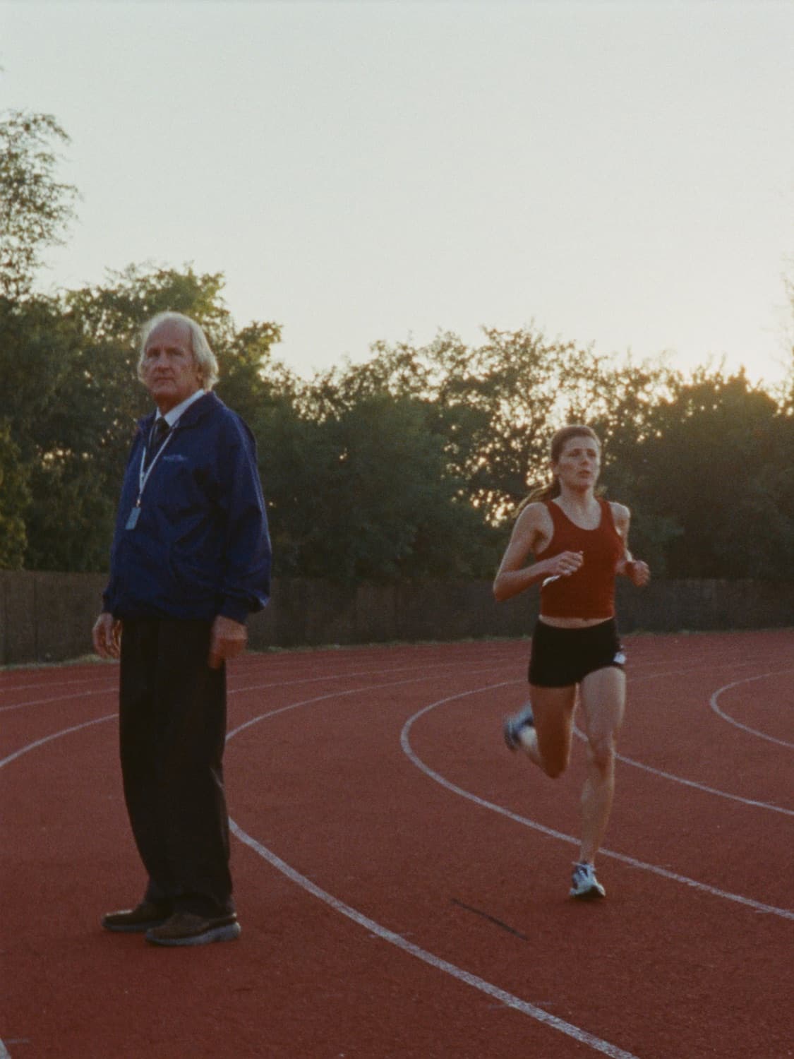 A running coach watching a runner come round the bend of a track