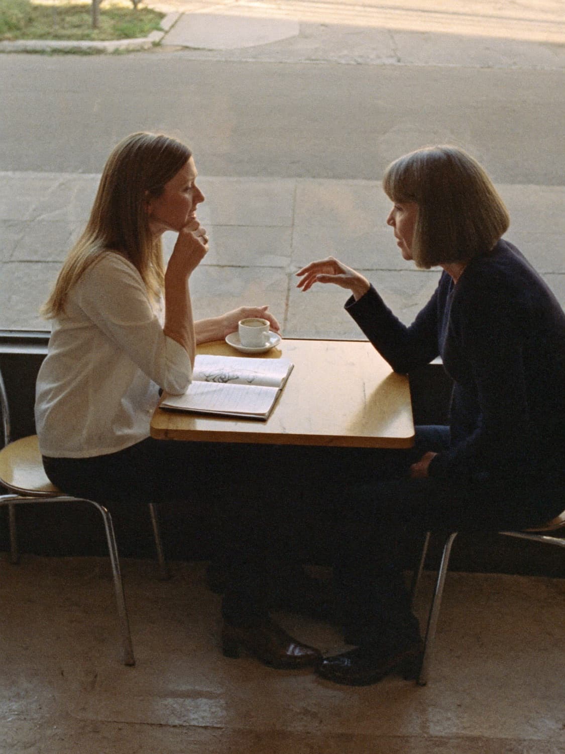 A career coach and a client talking over a notebook at a cafe table