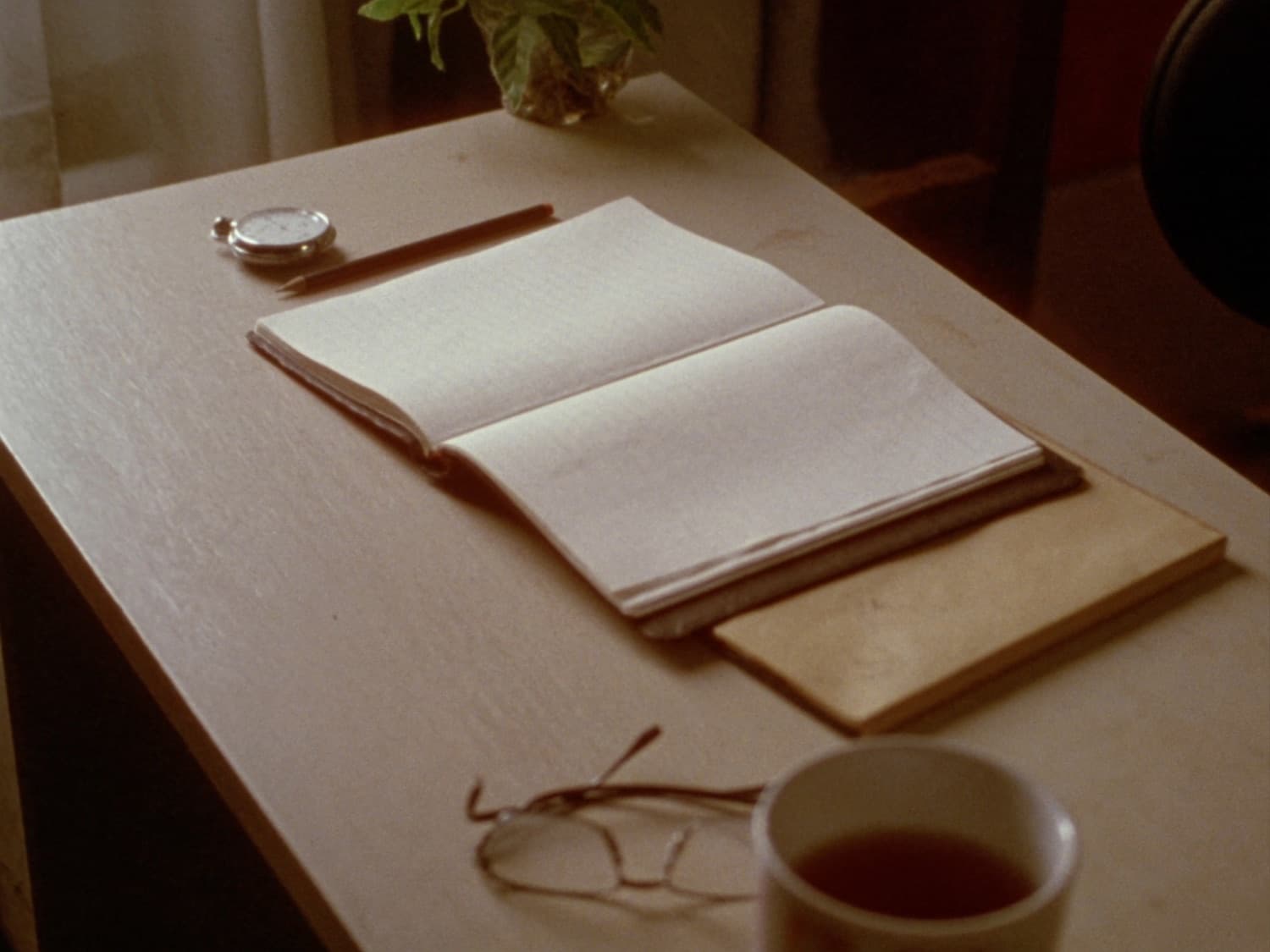 An open diary, a pencil and a mug of tea on a wooden desk