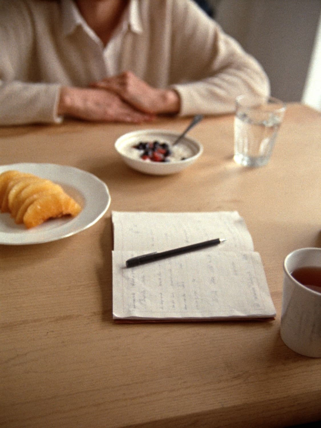 Breakfast, a glass of water and an open notebook on a kitchen table