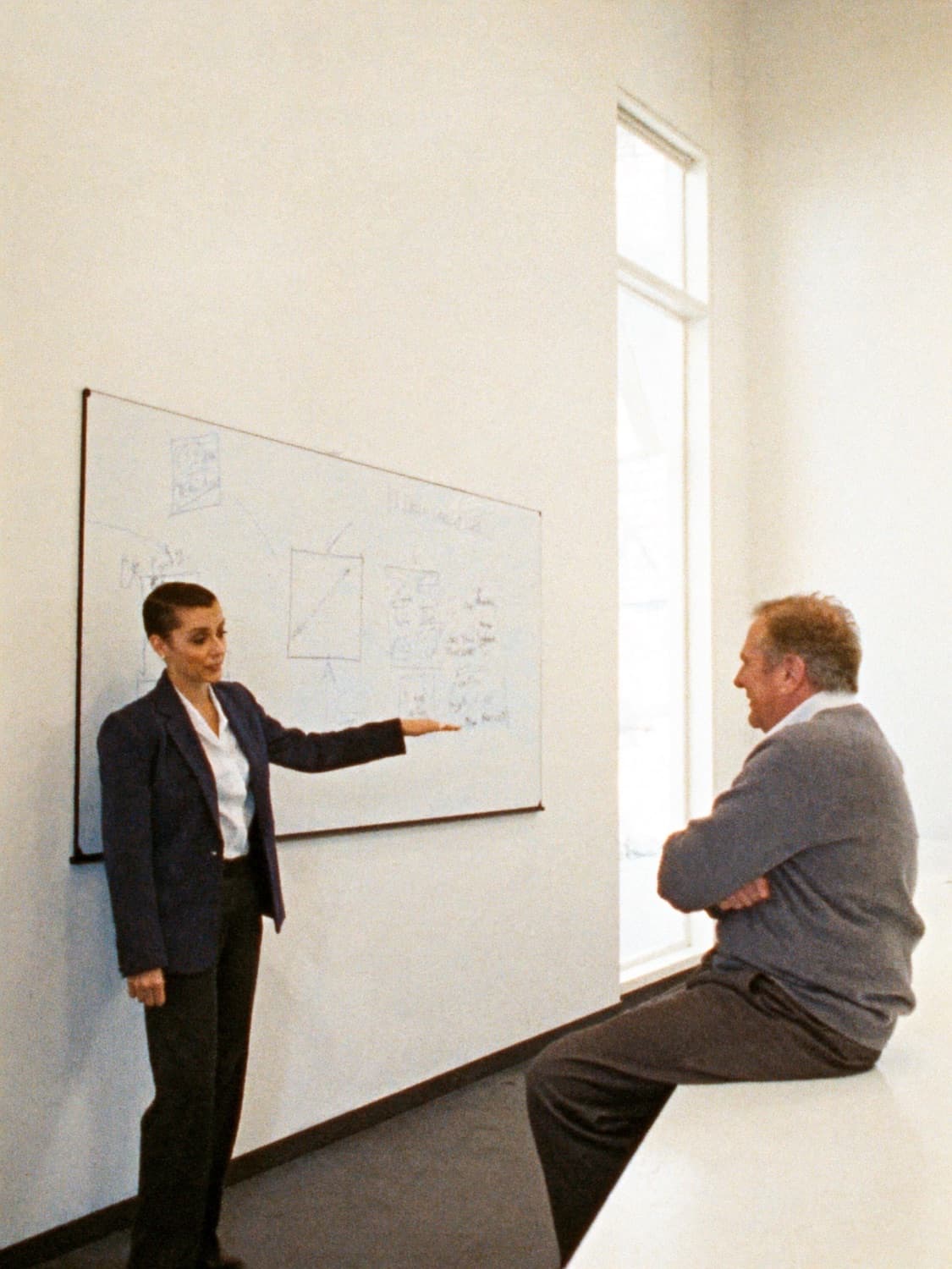 A manager talking through a plan at a whiteboard while her coach listens